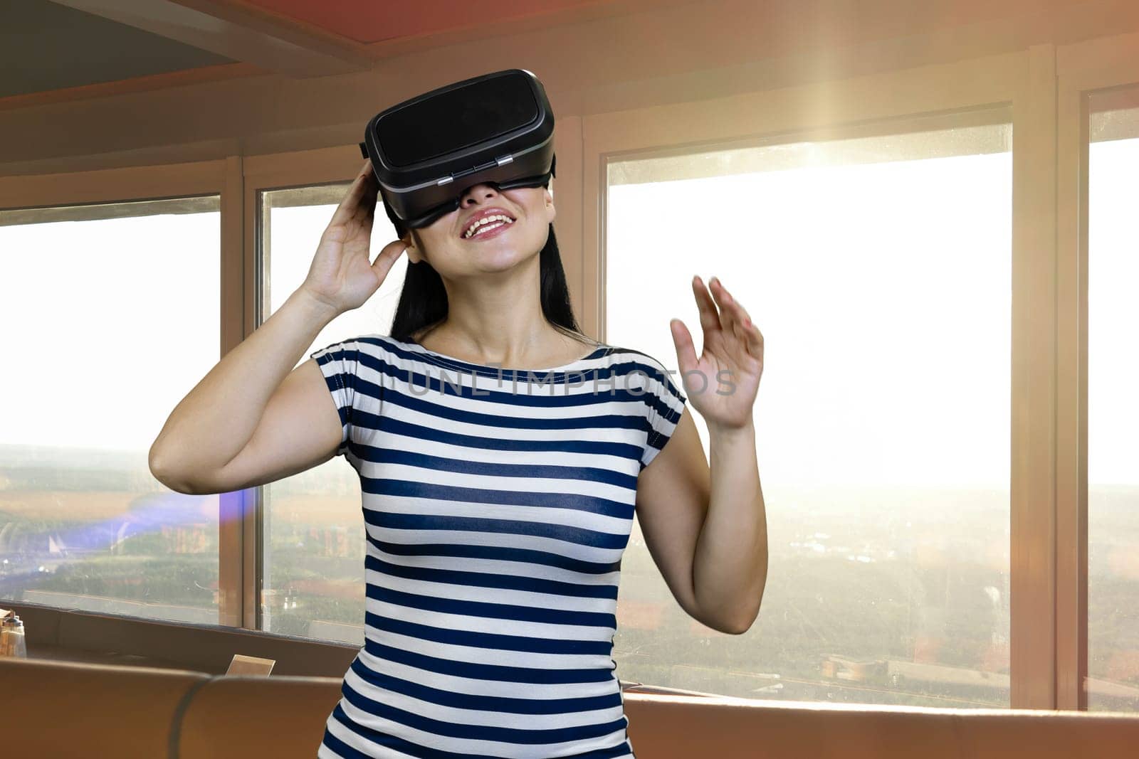 Portrait of a young brunette woman wearing headset. Indoor windows with sunlight on the background.