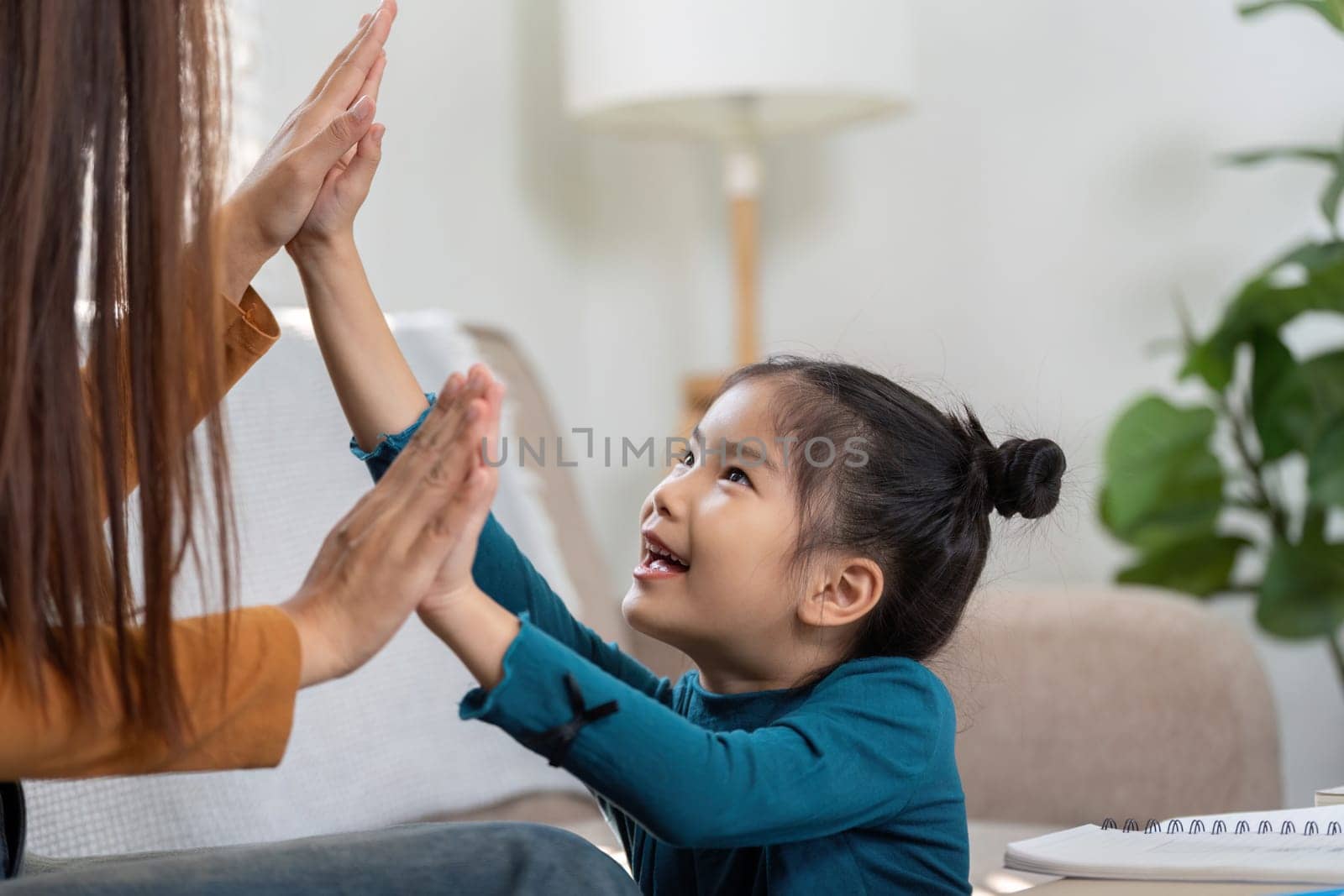 The girl shares a joyous high-five with her mother, emphasizing the playful side of learning and bonding.