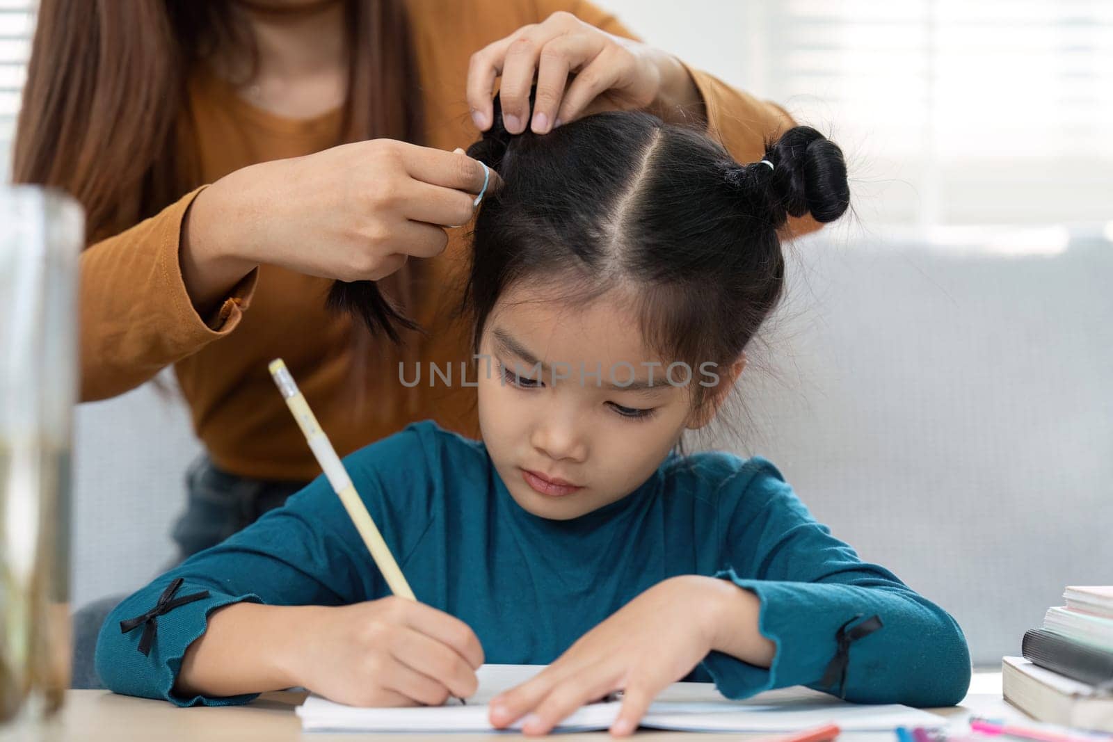 A nurturing figure assists a young girl in her studies, showing the importance of support in education. The moment captures a loving interaction around learning.