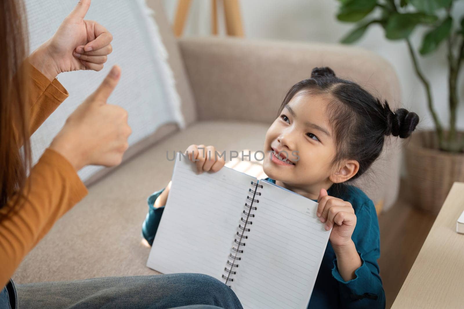 The girl proudly presents her notebook to her mother, receiving encouraging feedback and praise for her work.