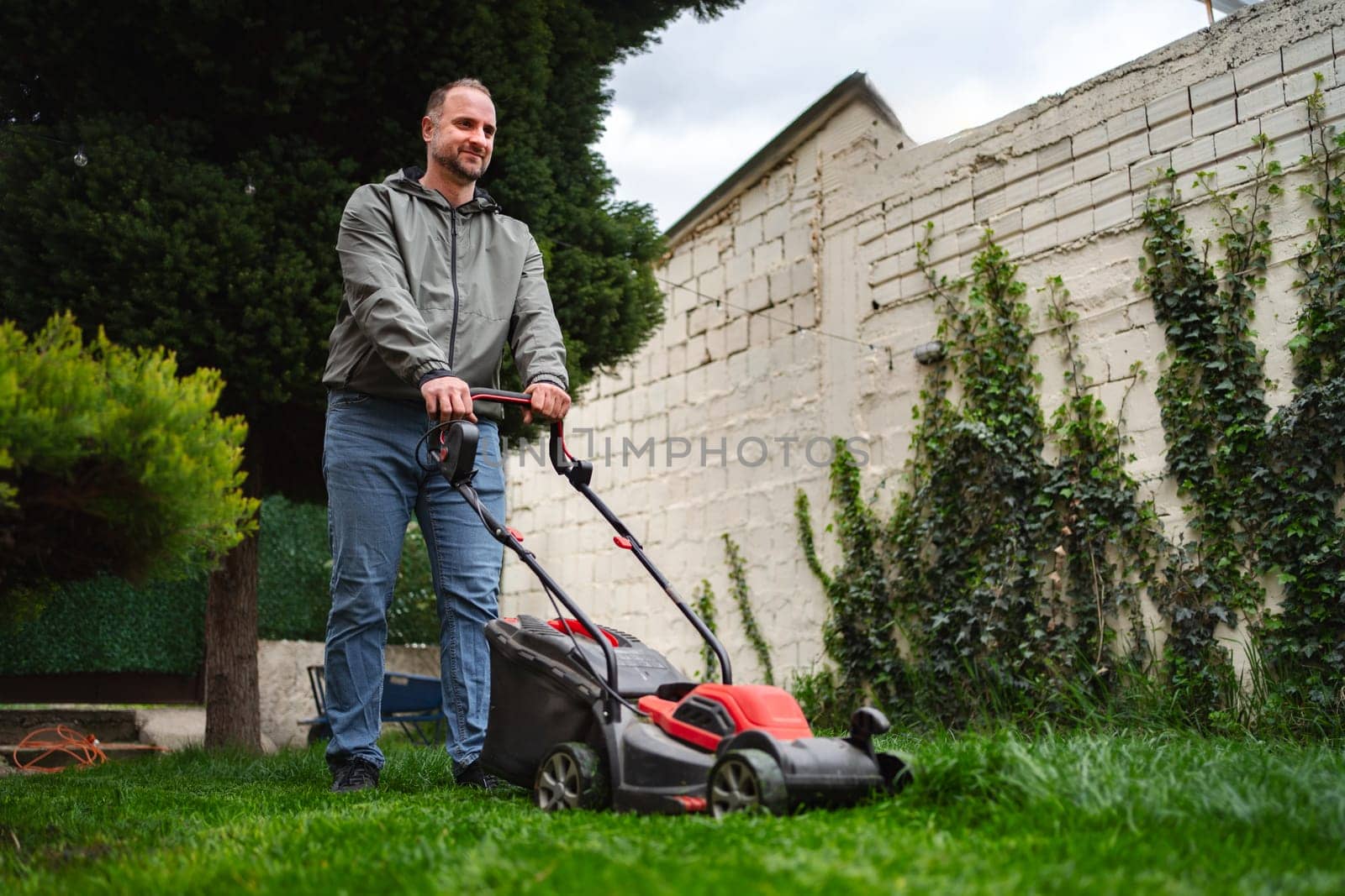 A relaxed afternoon where a man enjoys mowing the lawn in a vibrant garden. Lush greenery surrounds him as he skillfully trims the grass, creating a tidy outdoor space.