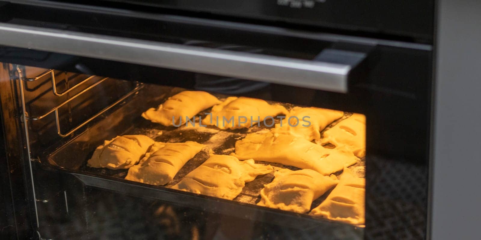 Puff pastries with cottage cheese filling baking in the oven
