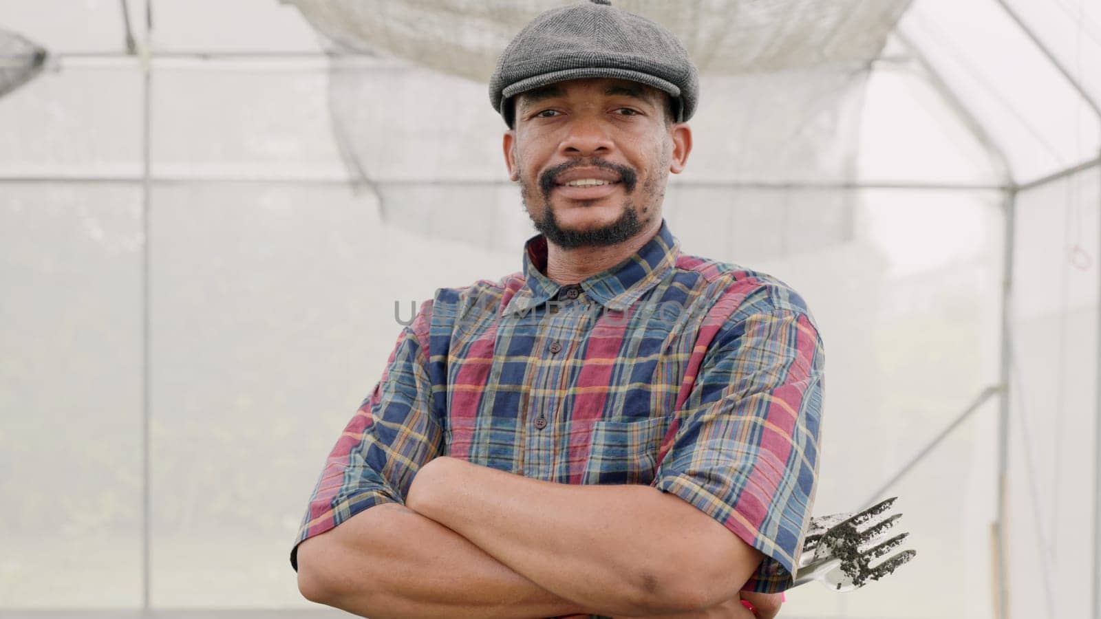 Portrait of confident farmer man standing with arms crossed on vegetable plantation in modern hothouse, Agriculture farming