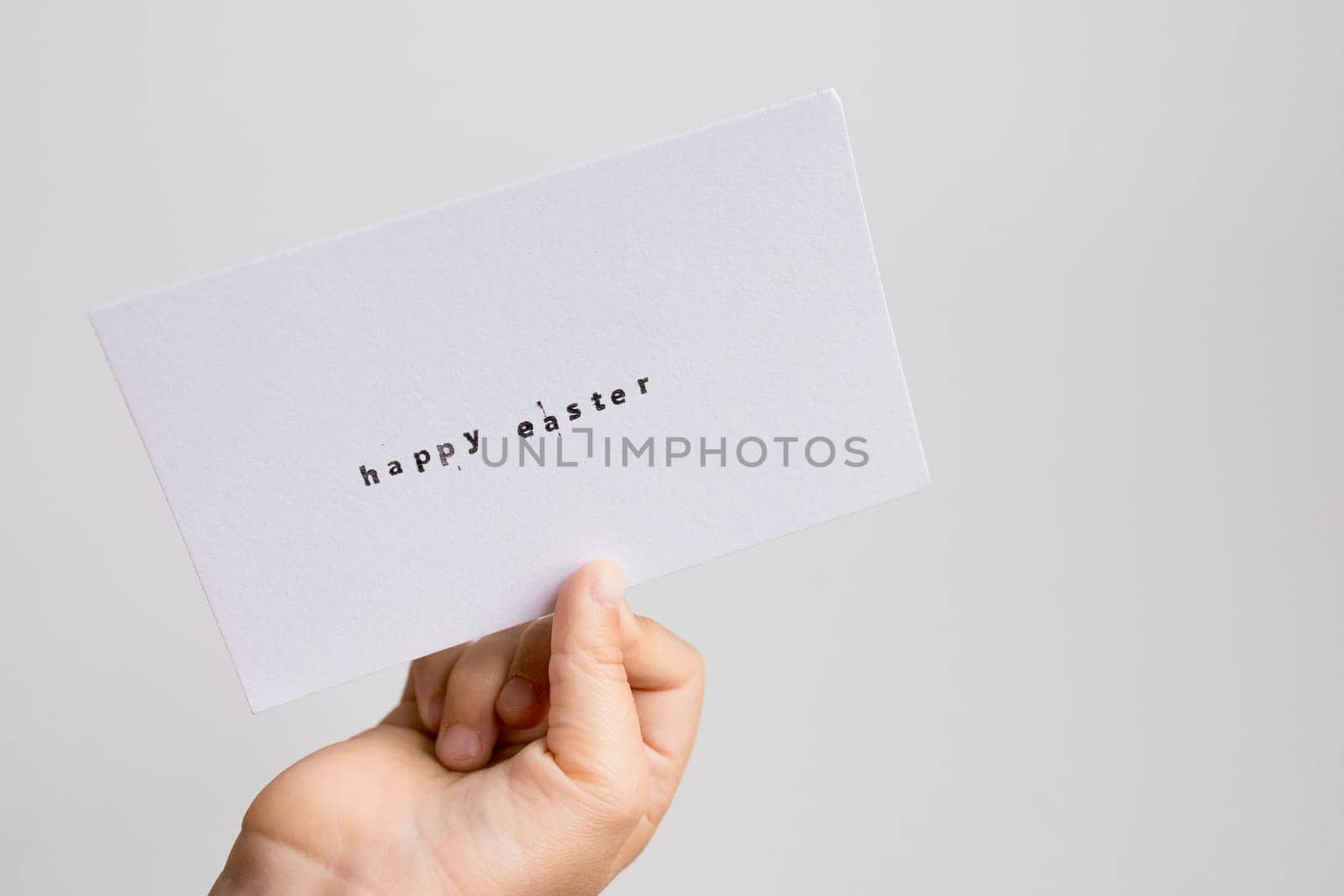 Caucasian child holding happy Easter card in hand.