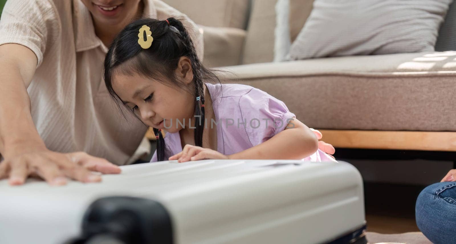In a friendly environment, an engaged mother and father encourage their daughter as she examines a suitcase, embodying fun and growth through play and imagination.
