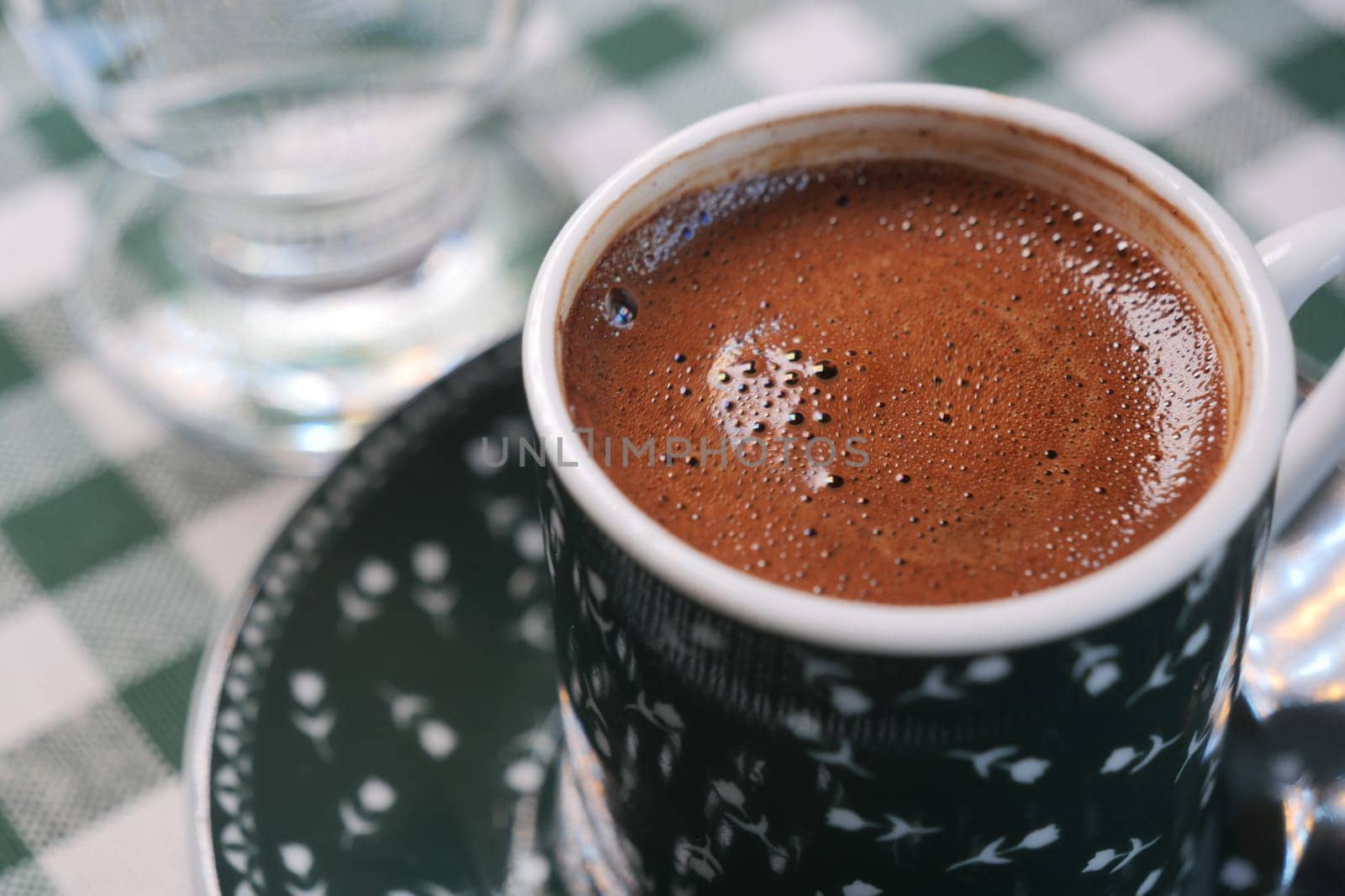 Enjoying turkish coffee in a cozy cafe setting with checkered tablecloth.