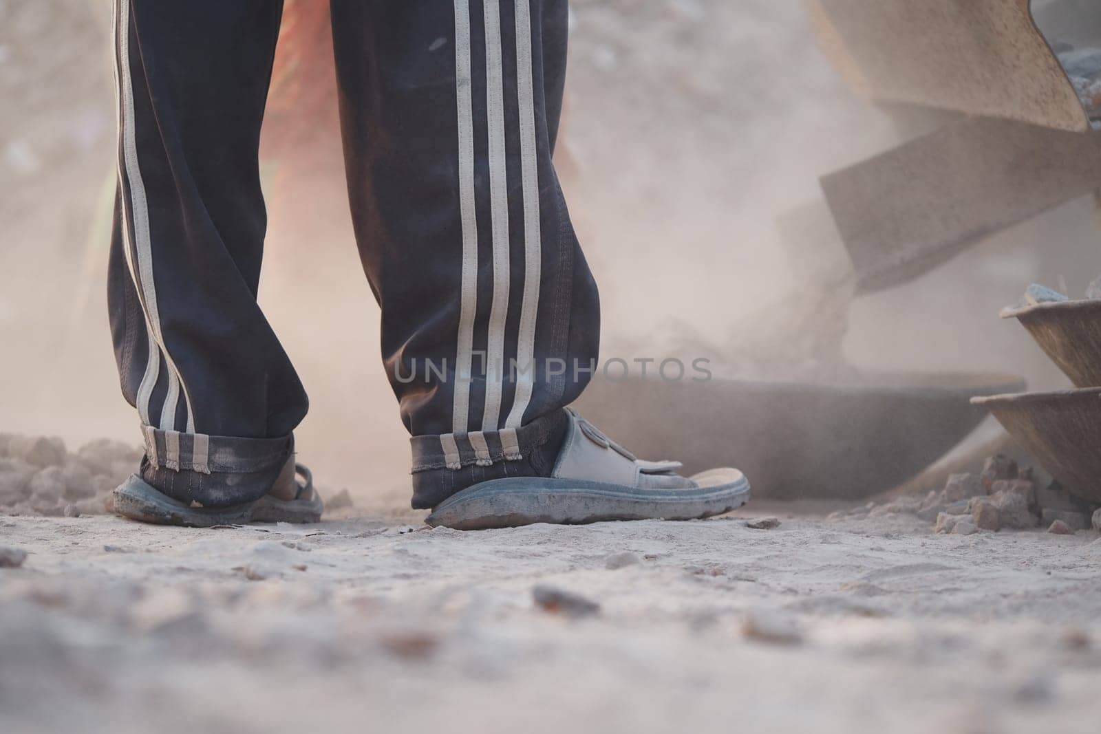 Construction worker stands amid dust and debris, focusing on tasks.