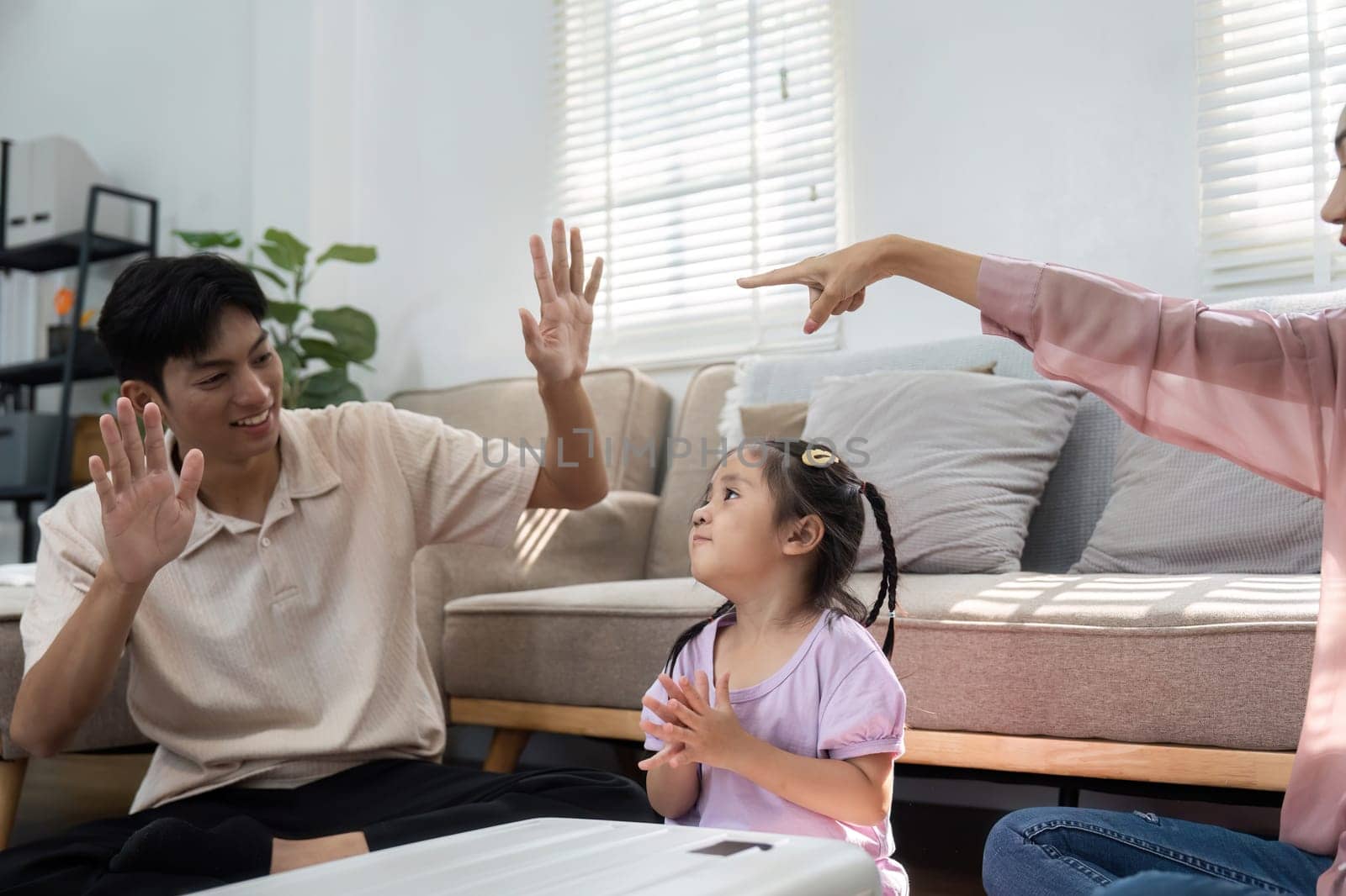 Using playful gestures, a father and mother encourage their daughter during family playtime, fostering connection as they celebrate the upcoming travels.