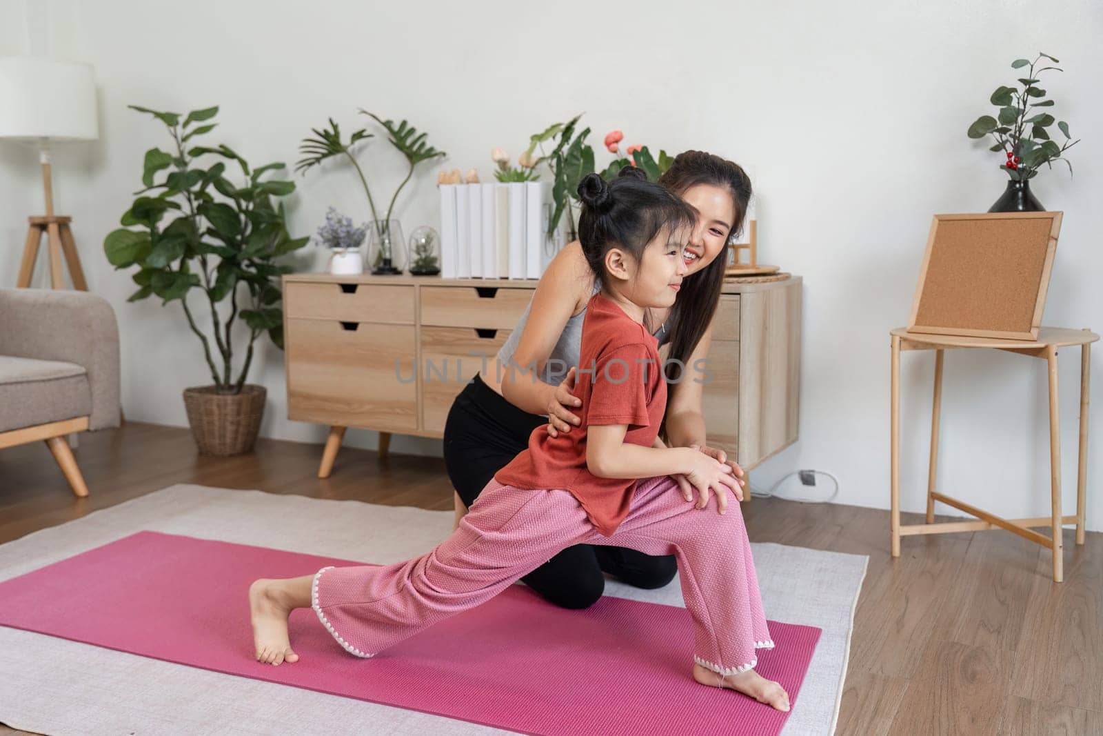 A mother guides her daughter during stretching exercises, promoting a healthy lifestyle while building a strong, supportive relationship.