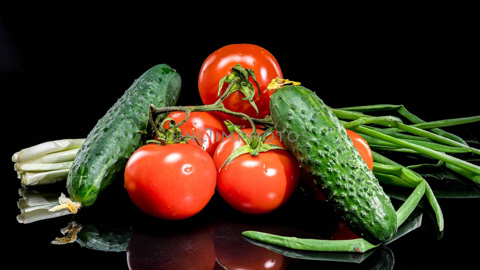 A close-up photo of fresh, ripe tomatoes and cucumbers arranged together, set against a black background, highlighting their vibrant colors and natural textures 
