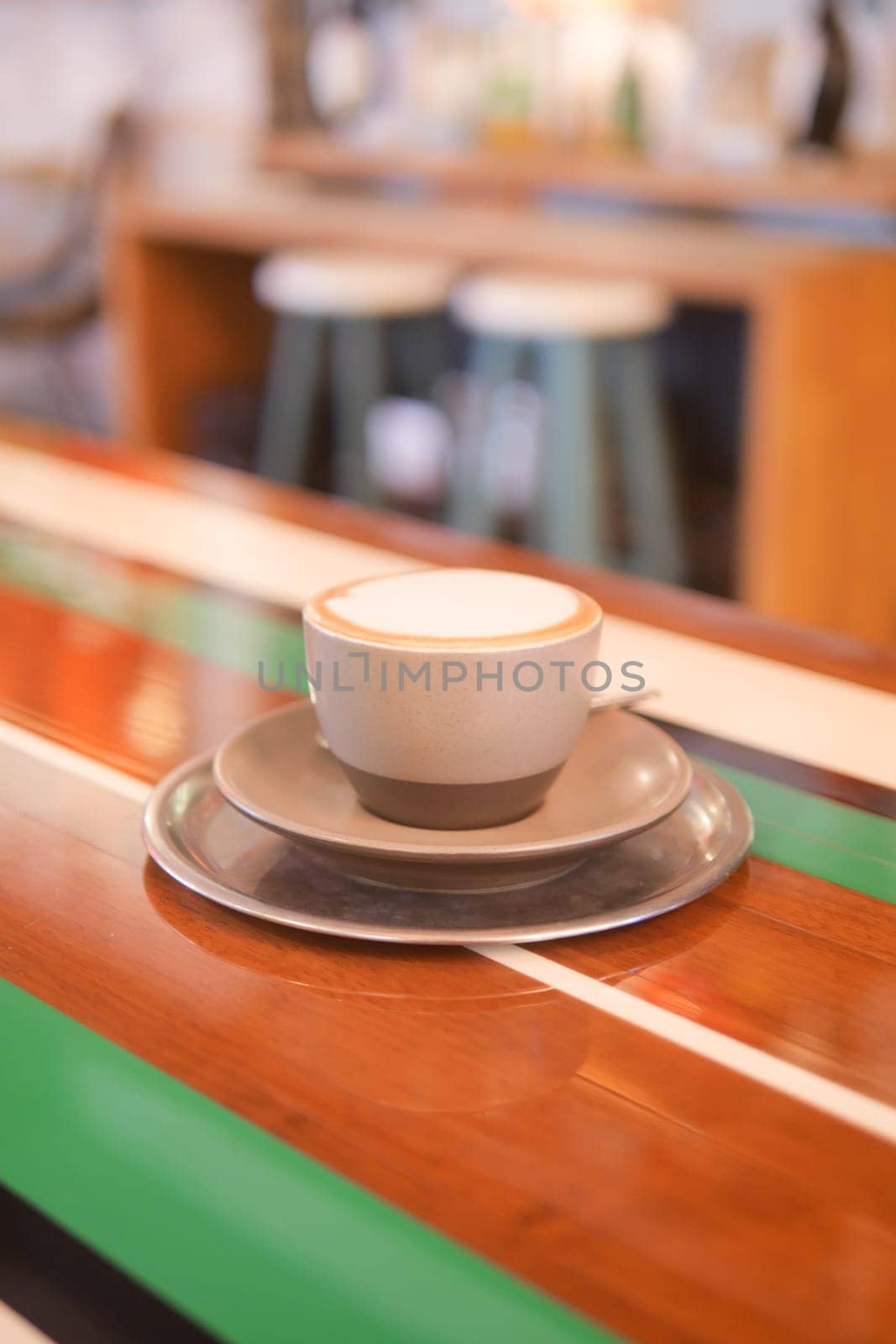 A warm coffee cup sits on a saucer ready to be enjoyed in a cafe.