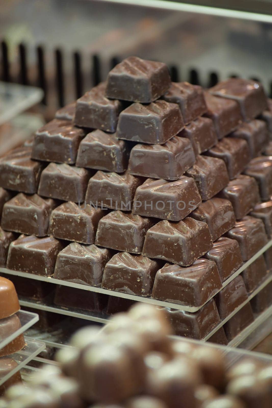 A pyramid of assorted chocolate treats fills a display case in a shop.