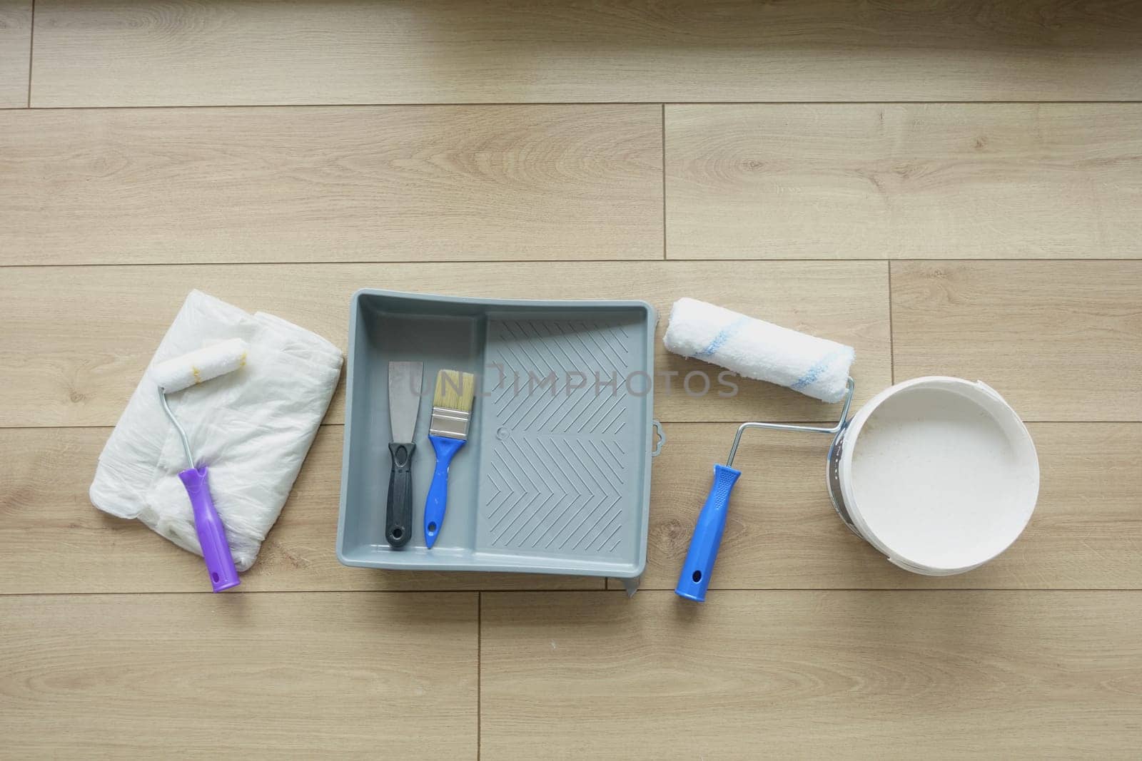 Set of painting tools neatly arranged on a wooden floor ready for use.