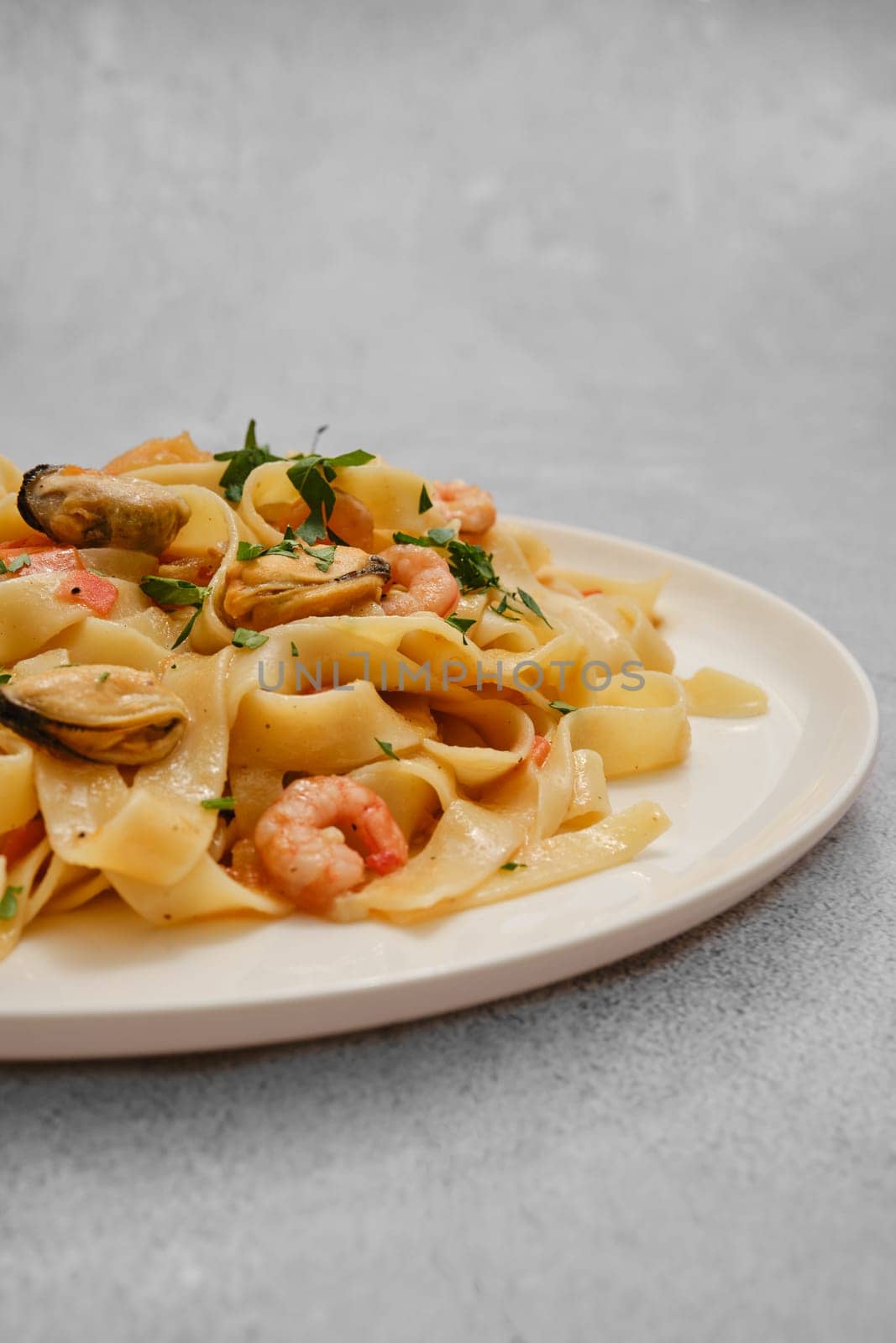 Close-up view of seafood pasta dish featuring fettuccine noodles tossed with shrimp and mussels, garnished with fresh herbs