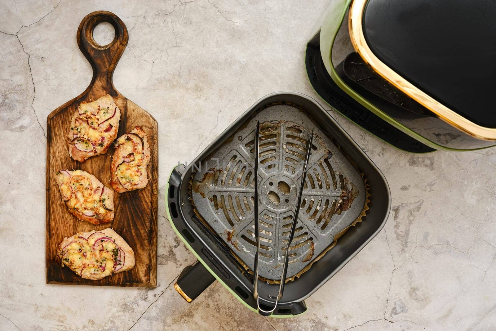 Juicy, golden-brown pork chops are arranged beautifully on a rustic wooden board, showcasing the perfect sear. An air fryer sits nearby, ready for more cooked delights.