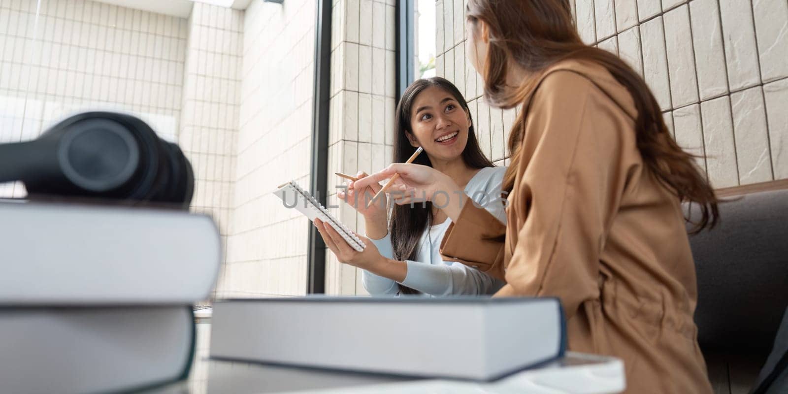 Two enthusiastic students discuss their coursework at a study table, showcasing the importance of collaboration in education.