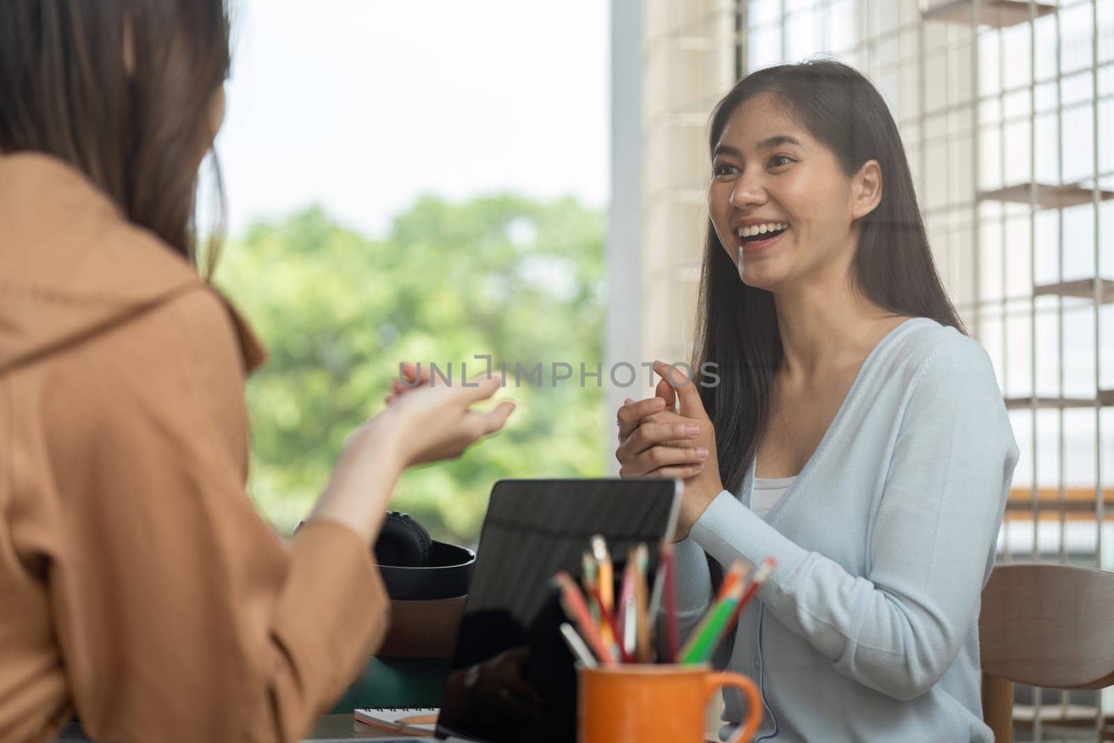 Two university students share ideas and solutions while studying together in a cozy environment filled with books and notes, showcasing teamwork and friendship.