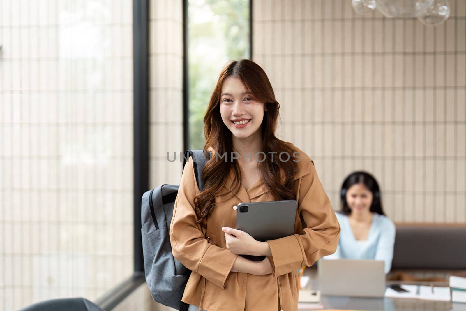 A cheerful student with her tablet, excited about her university journey, embodies personal growth and academic success.
