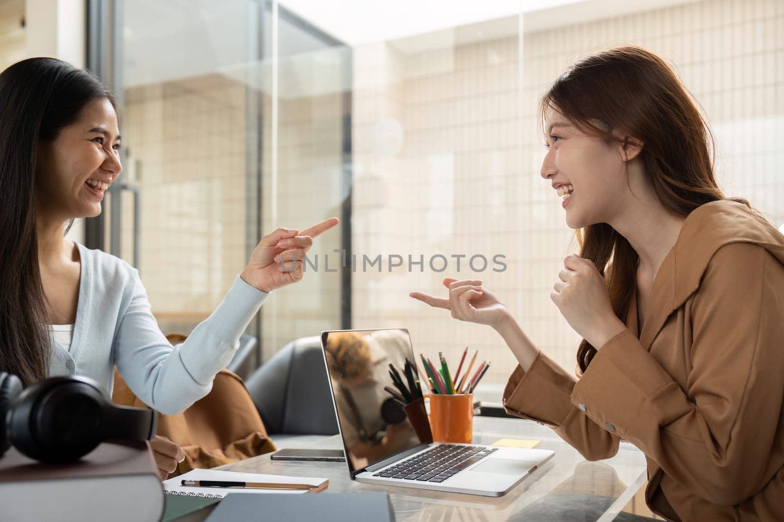In a bright study space, two students share a laugh while discussing their work, highlighting the joy of learning together.