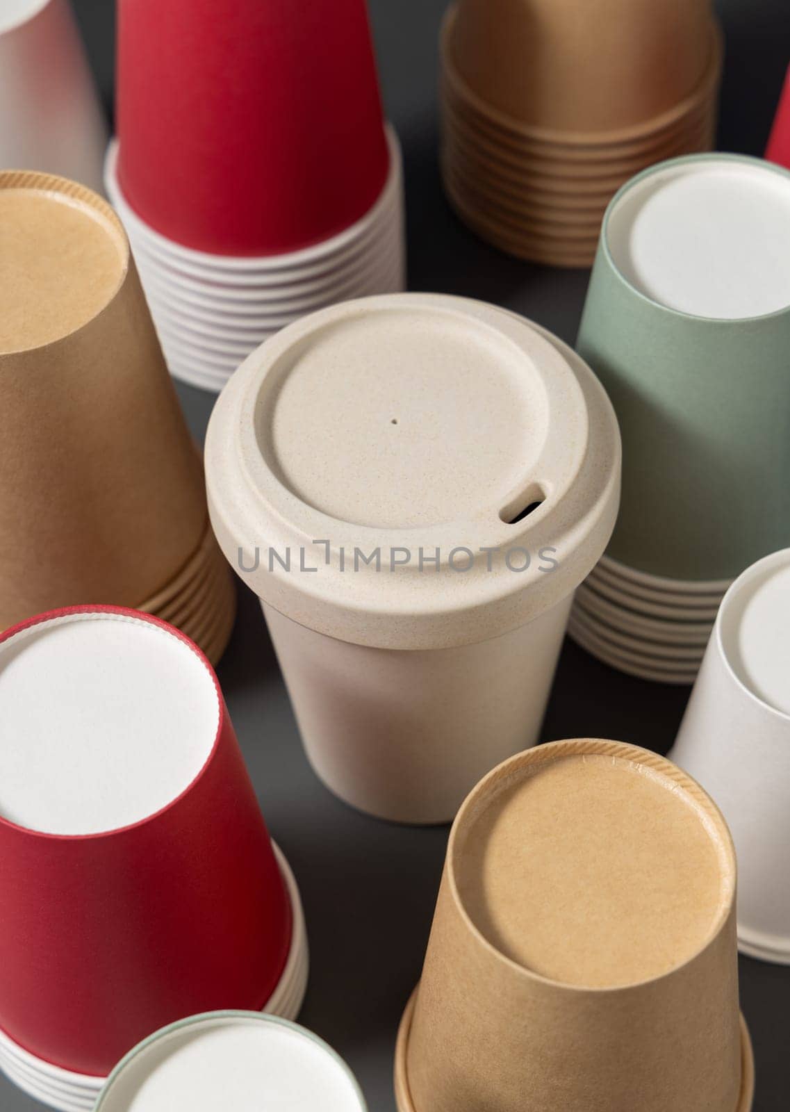 Disposable new multicolor paper cups and reusable bamboo coffee cup on gray closeup, mockup with copy space. Empty coffee cups. No plastic and sustainable lifestyle concept