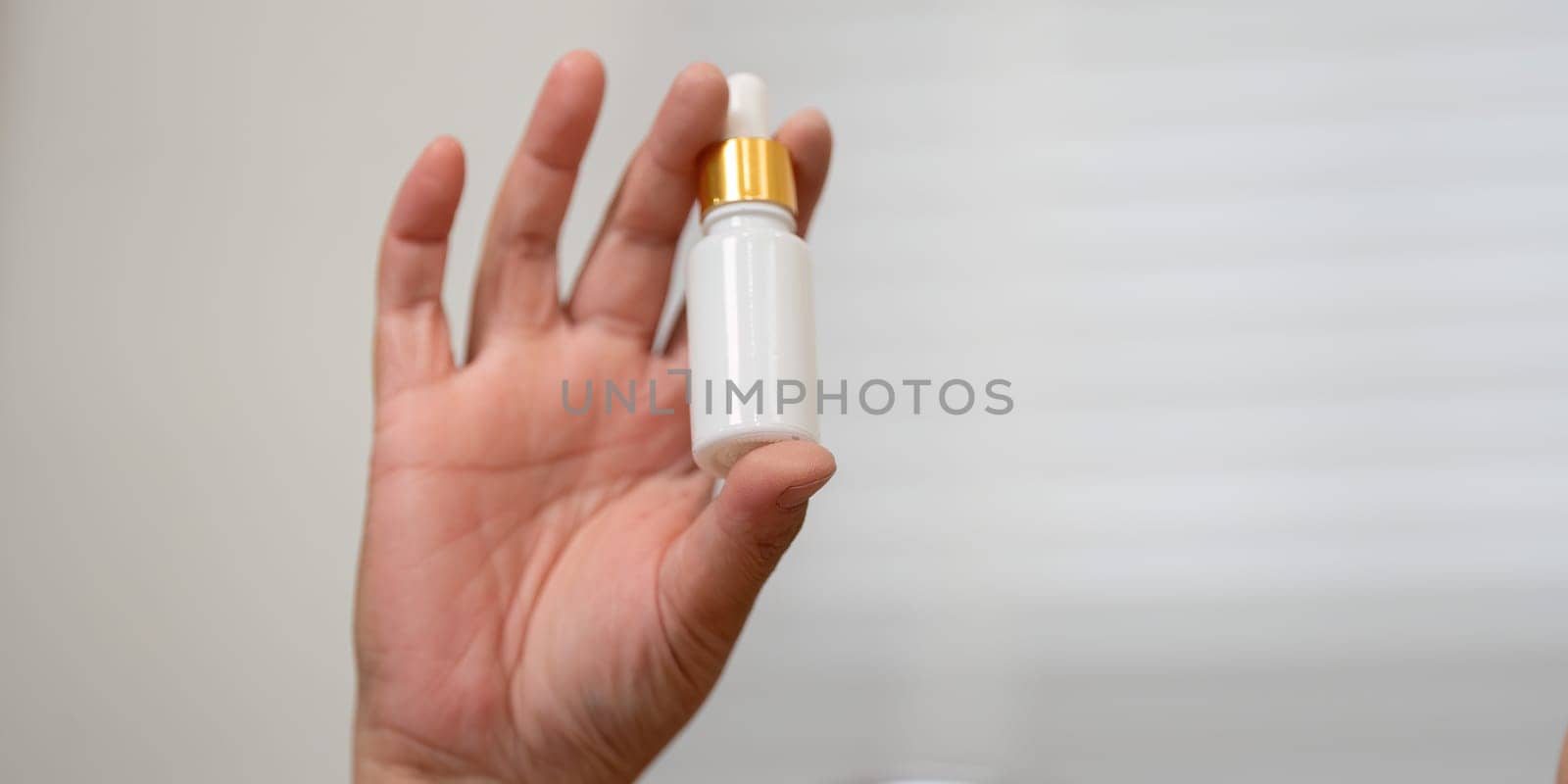 In a moment of focus, a hand presents a beauty serum dropper, underlining the importance of skincare in enhancing overall beauty and wellness.