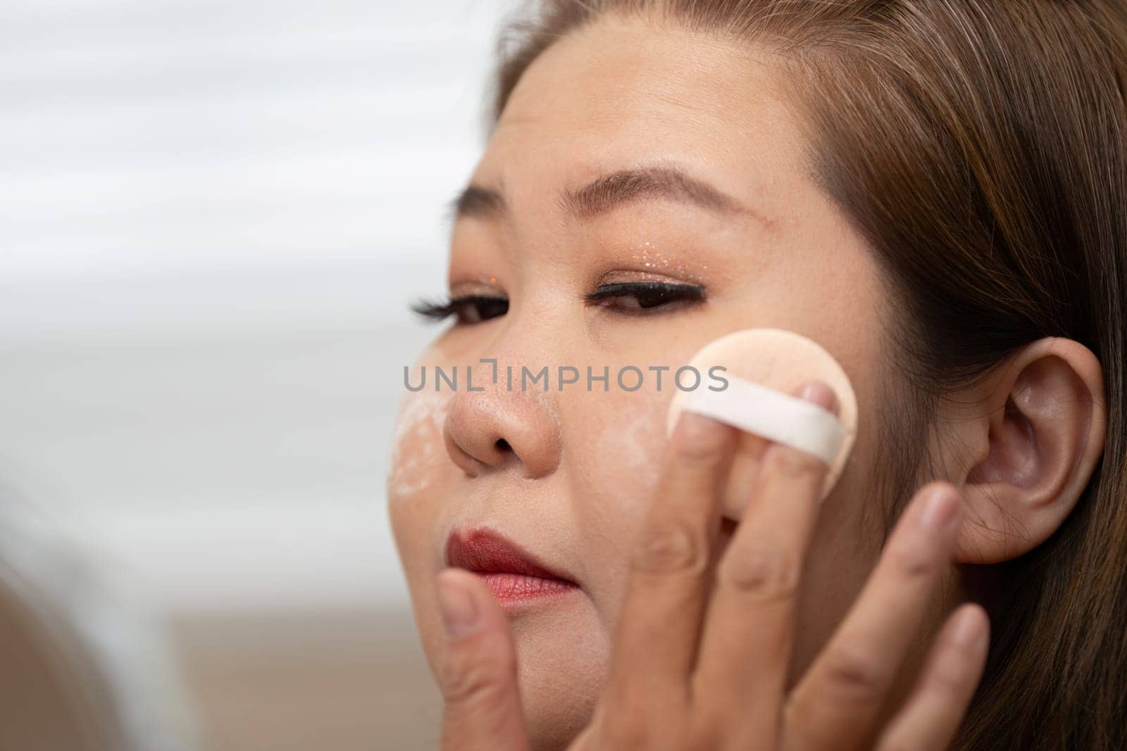 Focused on her makeup skills, a woman applies foundation with precision, emphasizing her artistry in beauty application and creating a flawless look.