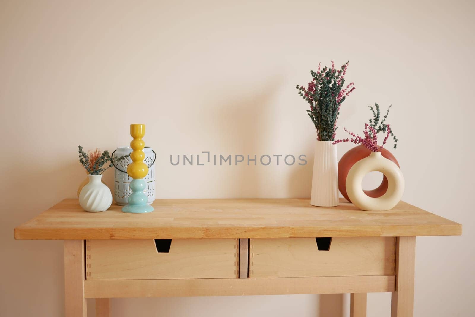 Wooden table displays colorful vases holding fresh flowers in a cozy space.