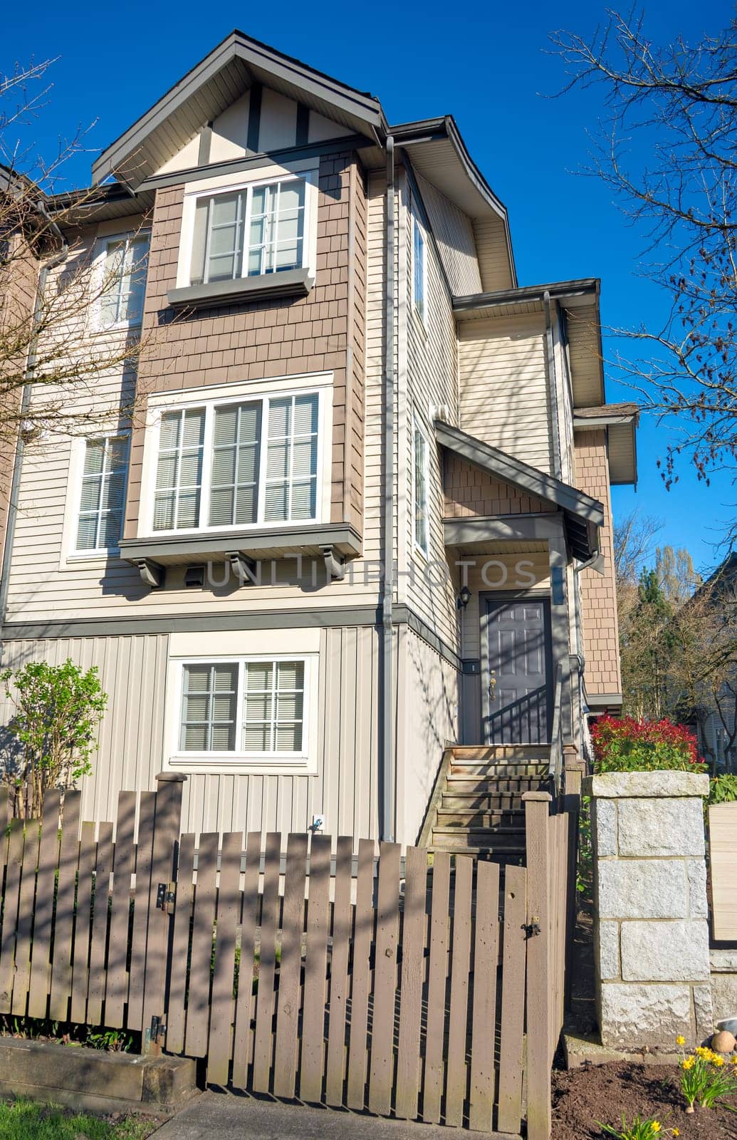 Residential townhouse entrance with wooden fence in front on early sprint day in Vancouver, Canada