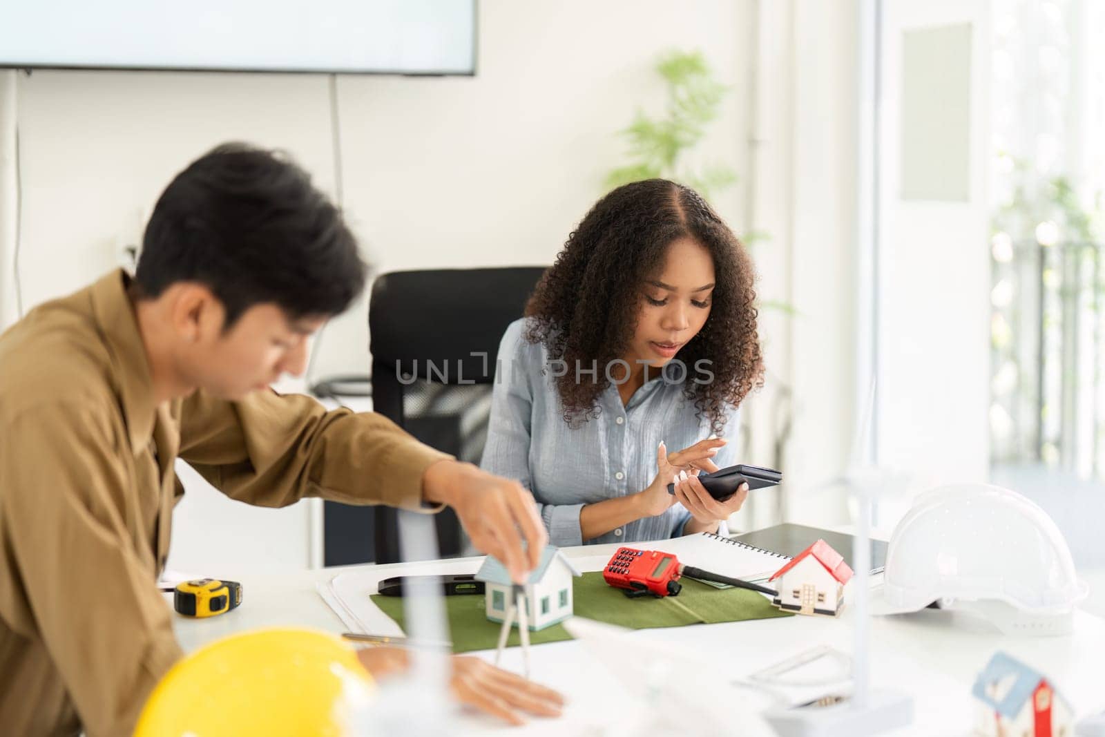 In this image, two colleagues engage in a dynamic conversation, examining sustainable housing models and discussing their effectiveness in modern living.