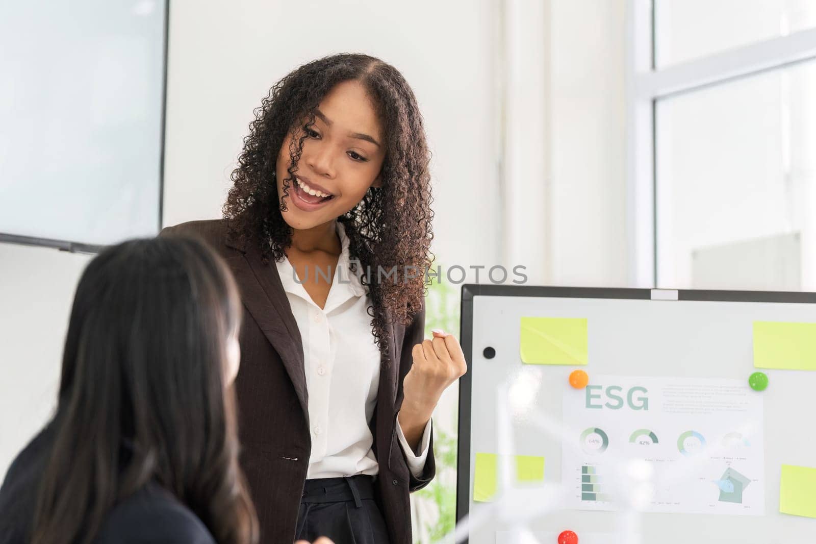 In a vibrant workshop, a woman communicates the importance of ESG initiatives to her colleagues, encouraging active participation and collaboration towards shared environmental goals.