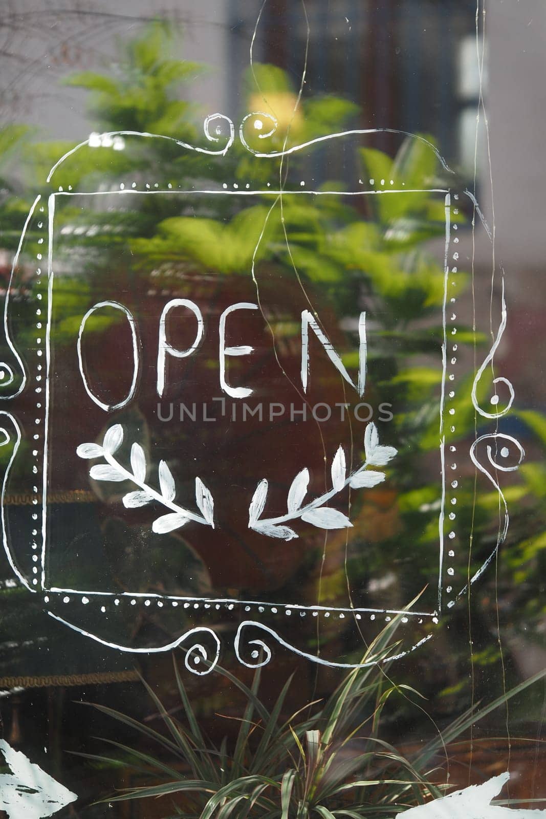 A hand-painted open sign is visible on a window surrounded by plants.