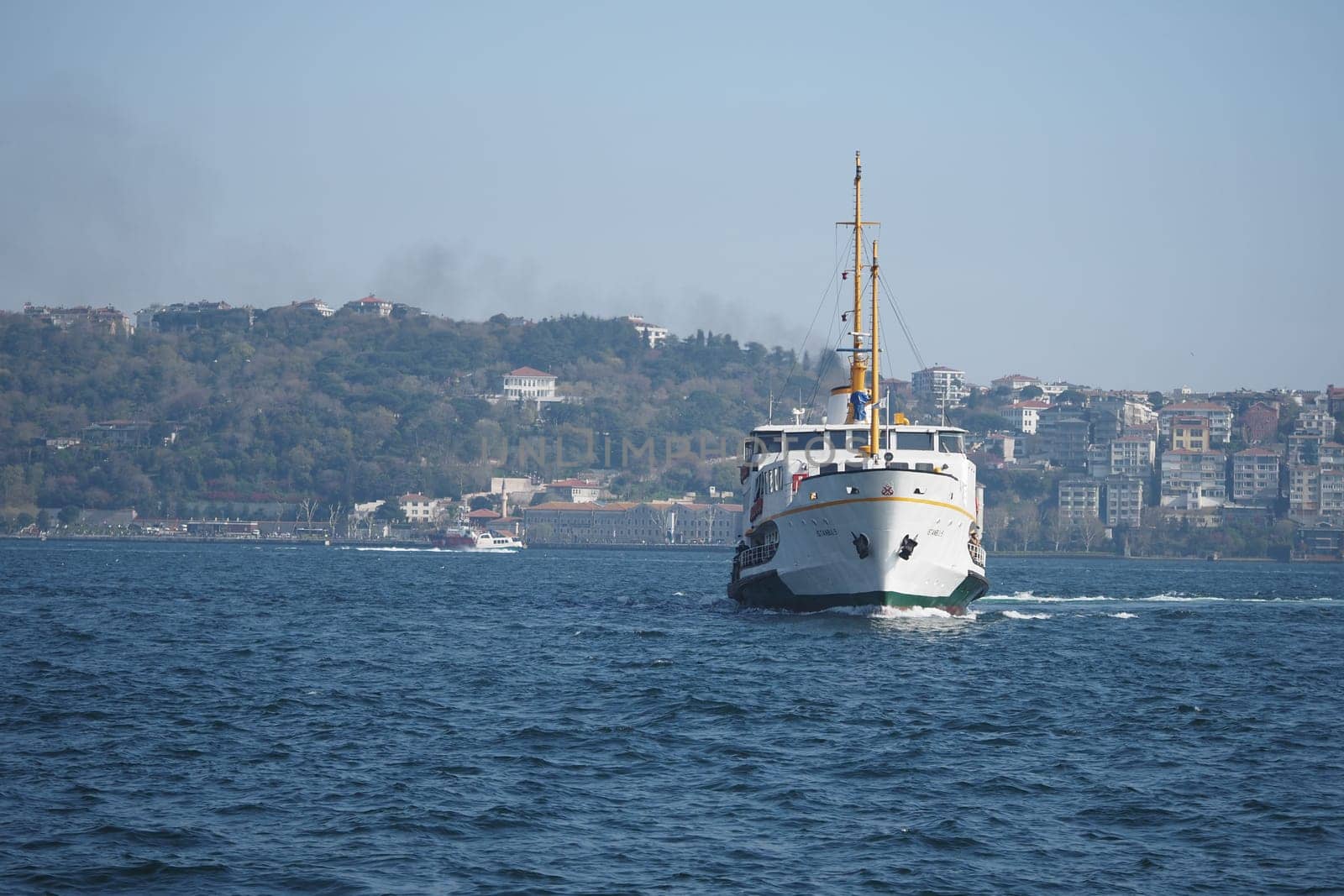 A ferry sails through the blue waters of Istanbul, surrounded by hills.