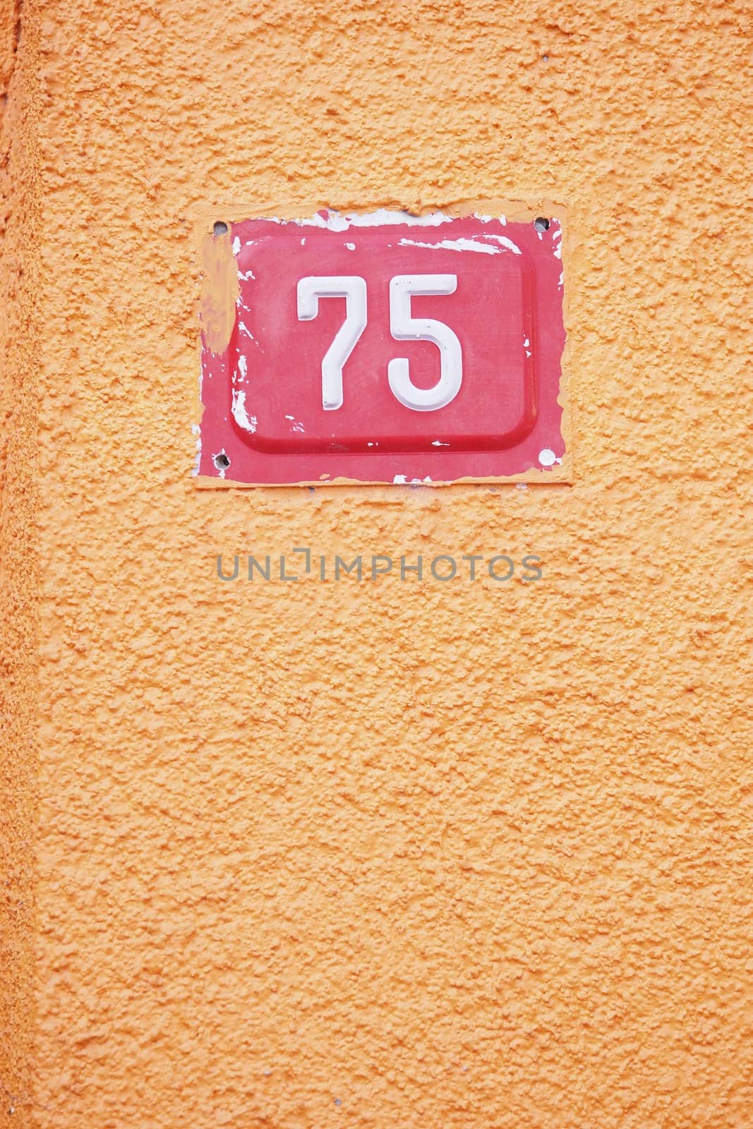 House number 75 is prominently displayed on the bright orange wall.