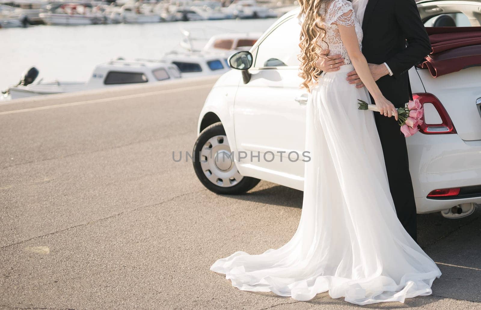 Elegant wedding couple holding a beautiful bouquet of pink roses.