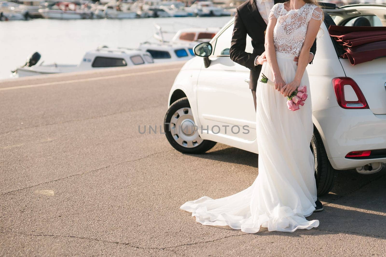 Elegant wedding couple holding a beautiful bouquet of pink roses.