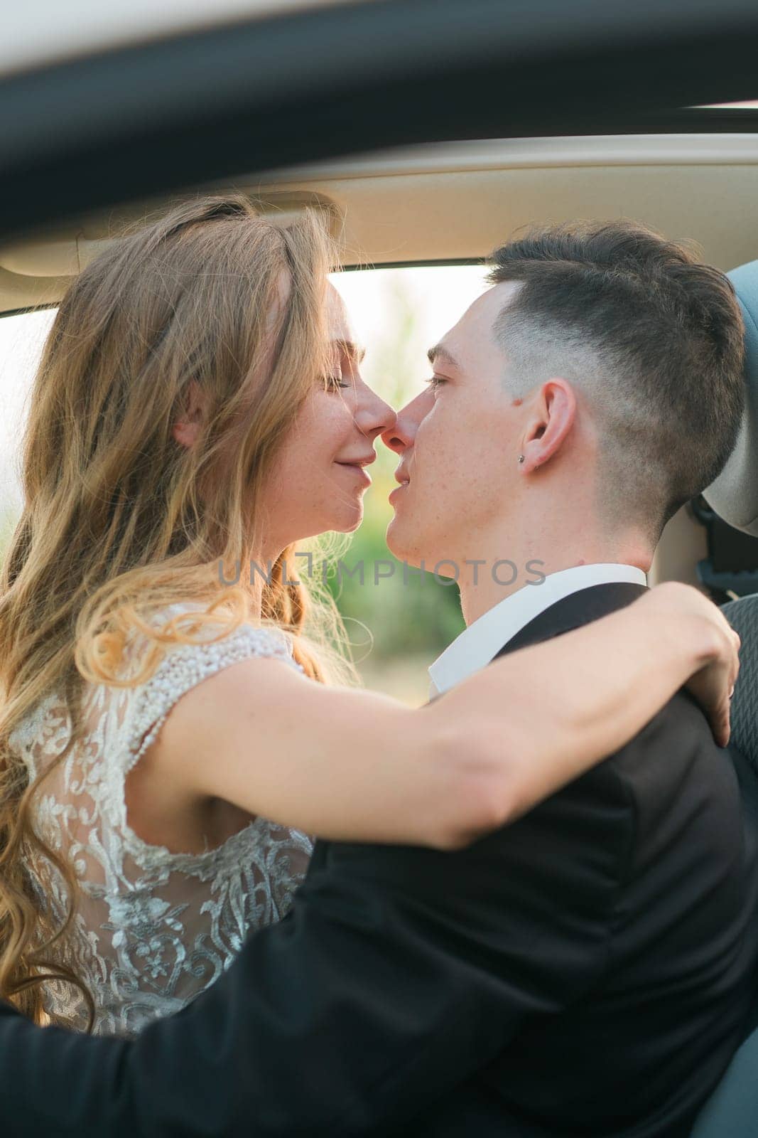 Couple about to kiss in a romantic embrace inside a car. Love, intimacy, connection and emotional closeness captured in a candid moment in wedding day.