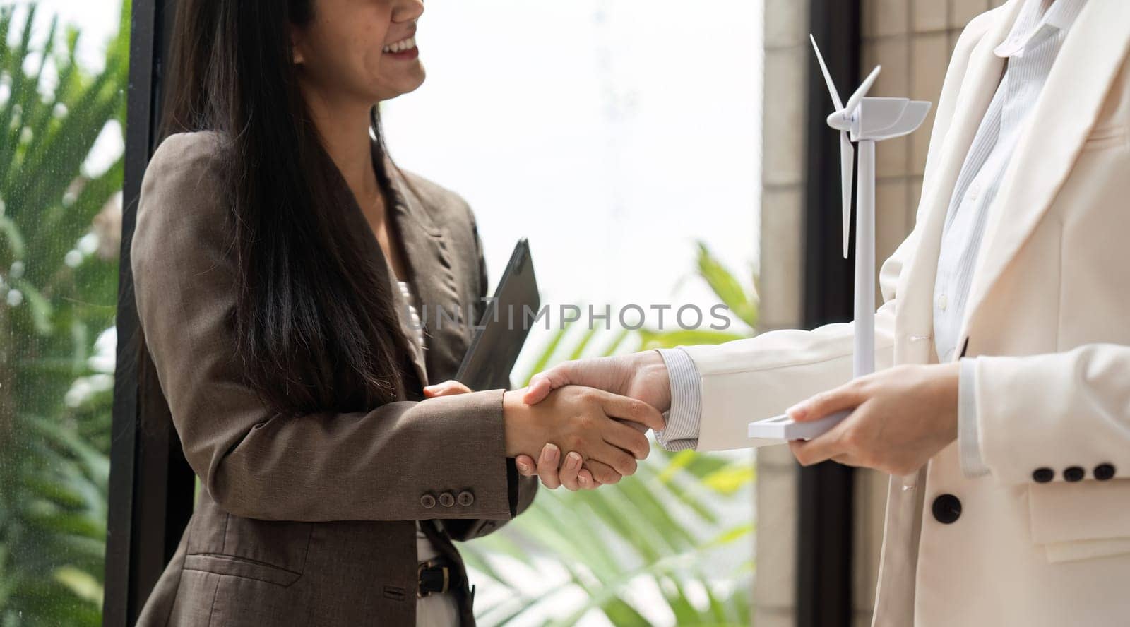 A moment of agreement as two women in business attire shake hands, signaling a partnership focused on environmental sustainability and innovative solutions.