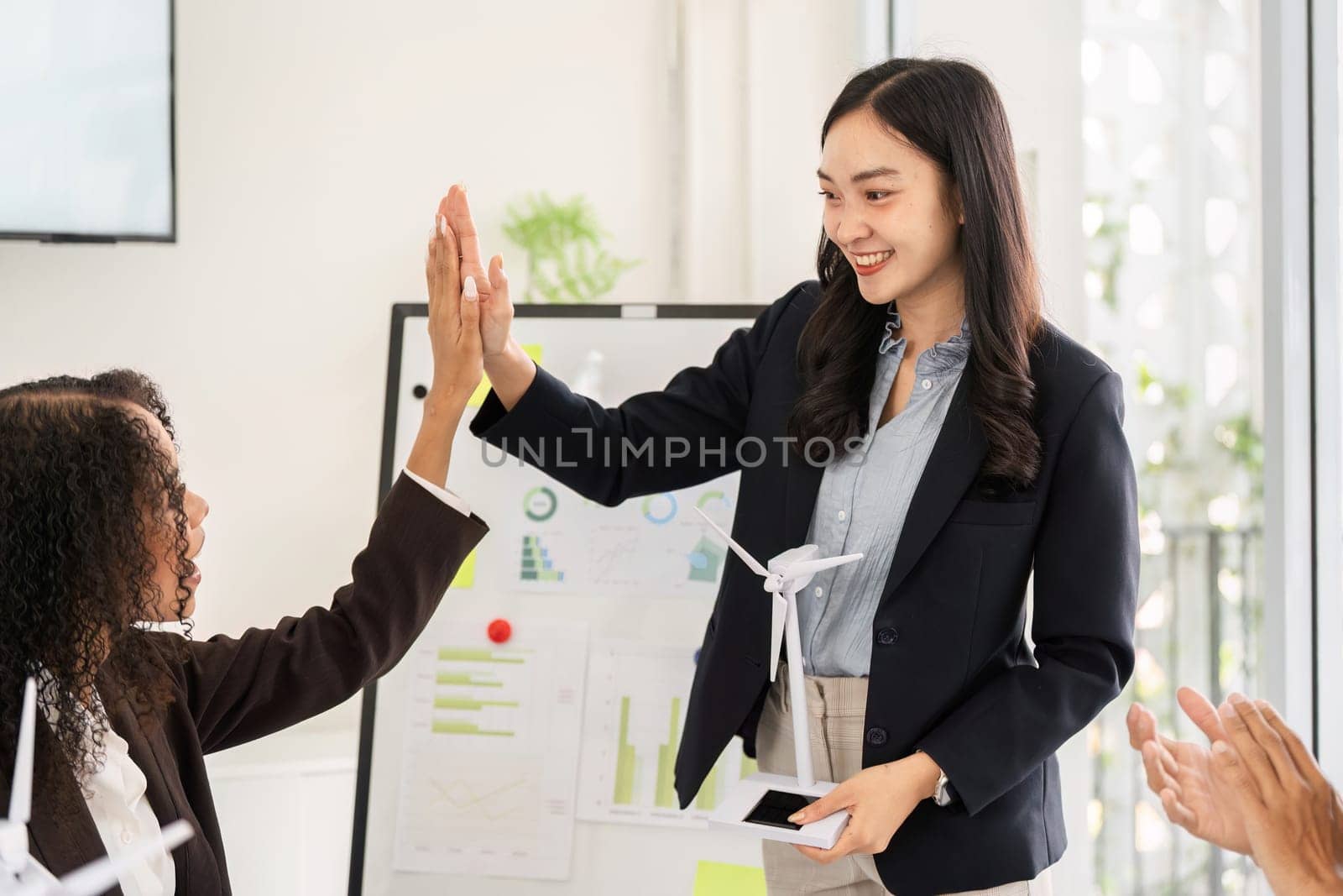 In a collaborative meeting, a speaker celebrates milestones with team members, highlighting achievements in sustainable energy projects, fostering enthusiasm and teamwork.