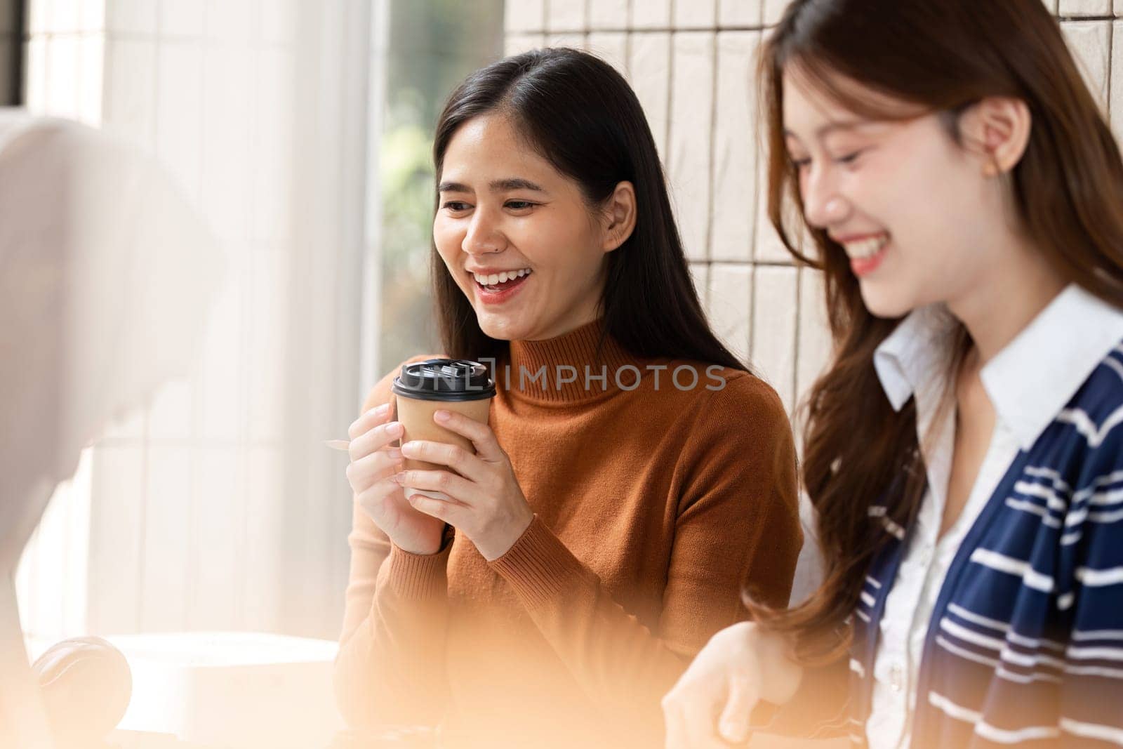 A cheerful student laughs and shares moments of joy over coffee with her friends, highlighting warmth and connection in a cozy environment.