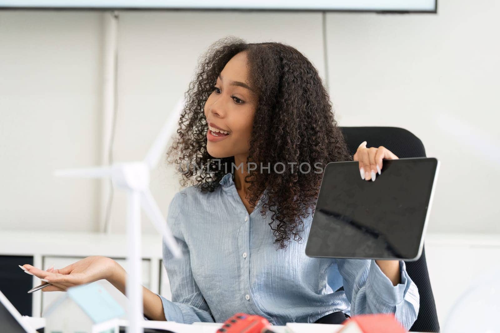 A passionate advocate for sustainable practices shares innovative ideas on renewable energy while presenting data on a tablet, highlighting eco-friendly technologies.