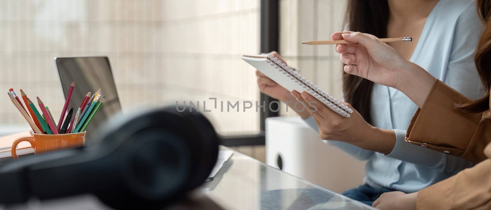 Two university students collaborate over their notes and laptop in a cozy study environment, exchanging thoughts with enthusiasm and support.