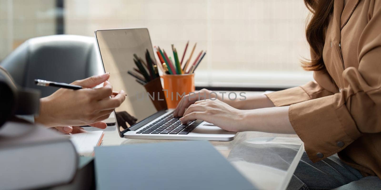 A focused university student engages in a study session, utilizing a laptop and collaborating with peers. The atmosphere highlights concentration and teamwork.