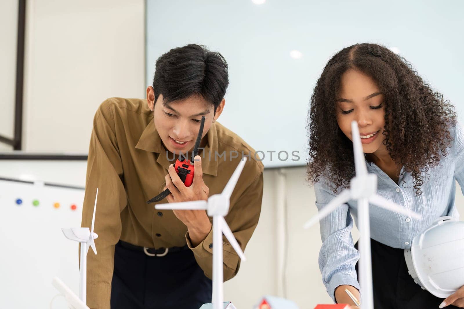 Focused collaboration between two professionals as they discuss their findings and strategies while working with wind energy models.
