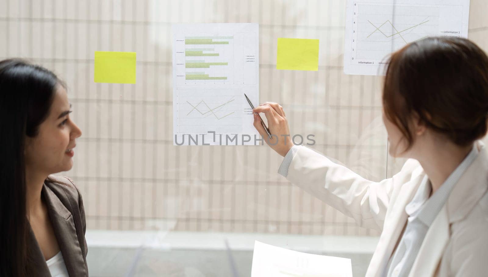 In a modern office, a woman points out key findings in ESG data, while her colleague observes, emphasizing the importance of informed decision-making in sustainability.
