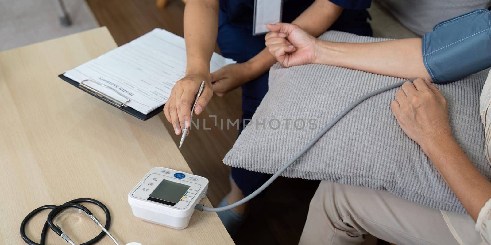 A dedicated caregiver measures the blood pressure of an elderly woman in a comfortable home environment, showcasing the importance of periodic health checks.