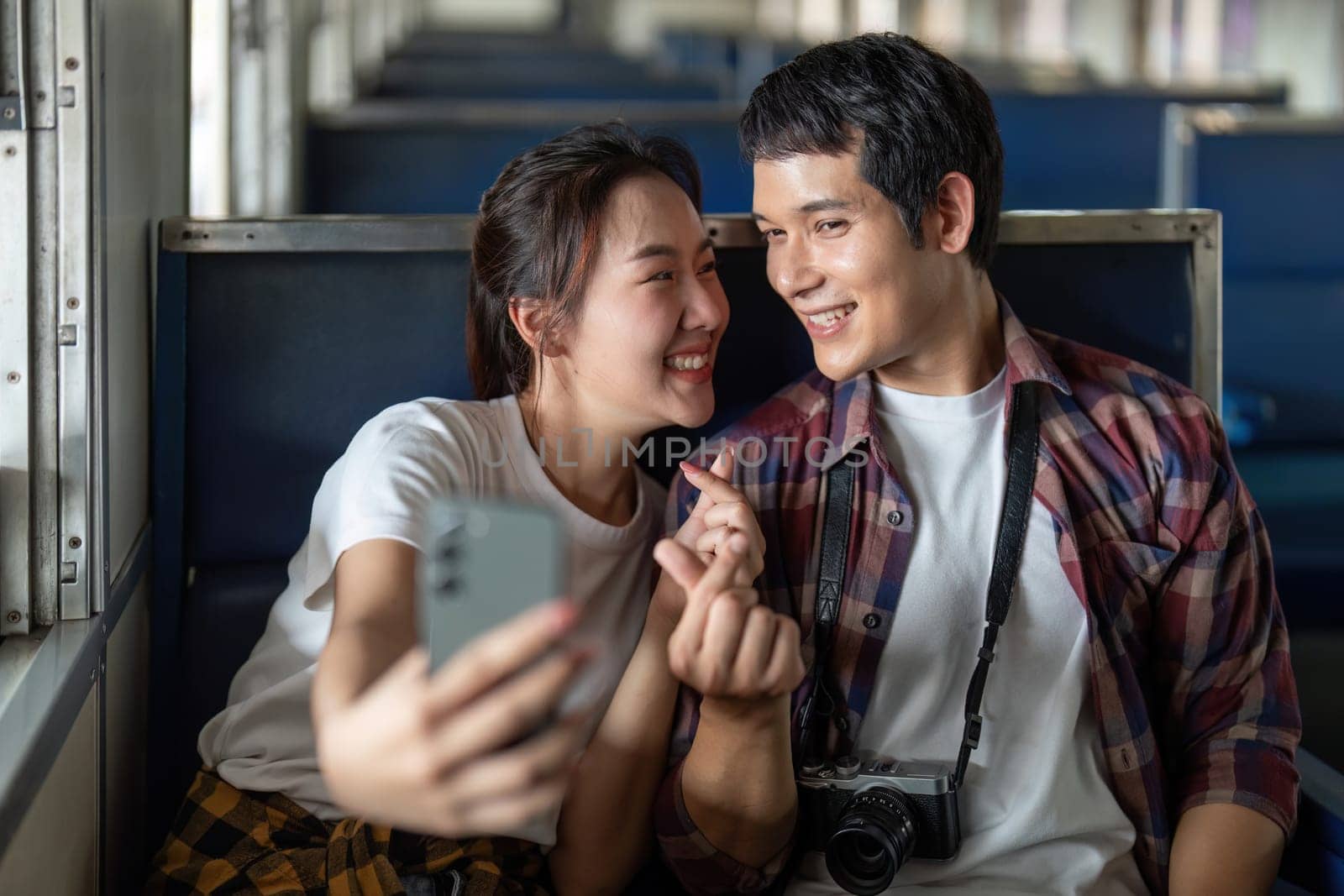 Inside a train, a couple takes a selfie, their smiles radiating happiness. The moment encapsulates the joy of shared experiences while traveling.