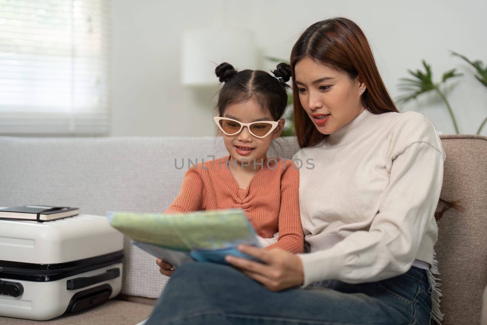 As they get ready for an exciting trip, the mother and daughter share a moment of exploration over a map, discussing potential destinations to visit.