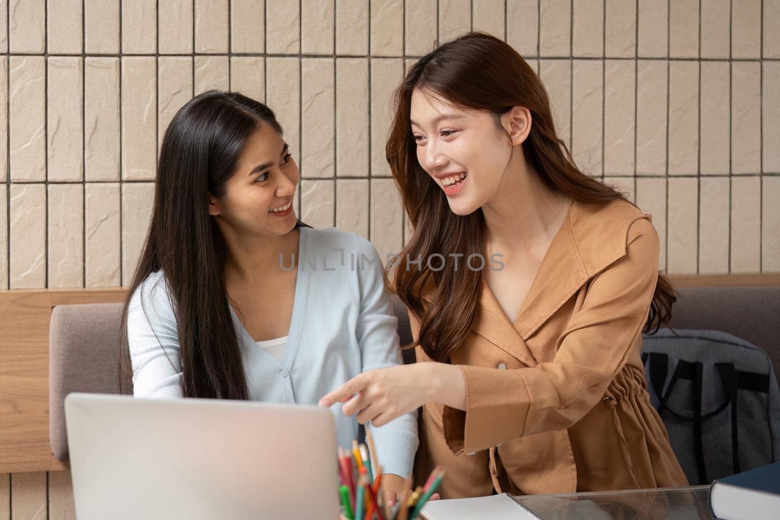 Two friends engage in a lively discussion while working on their laptops, sharing ideas and solutions in an inspiring study atmosphere.