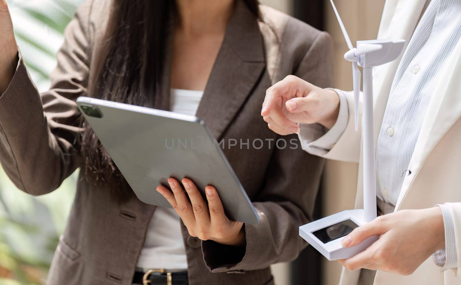 Two women discuss renewable energy solutions while engaging with technology, highlighting modern approaches to sustainability.