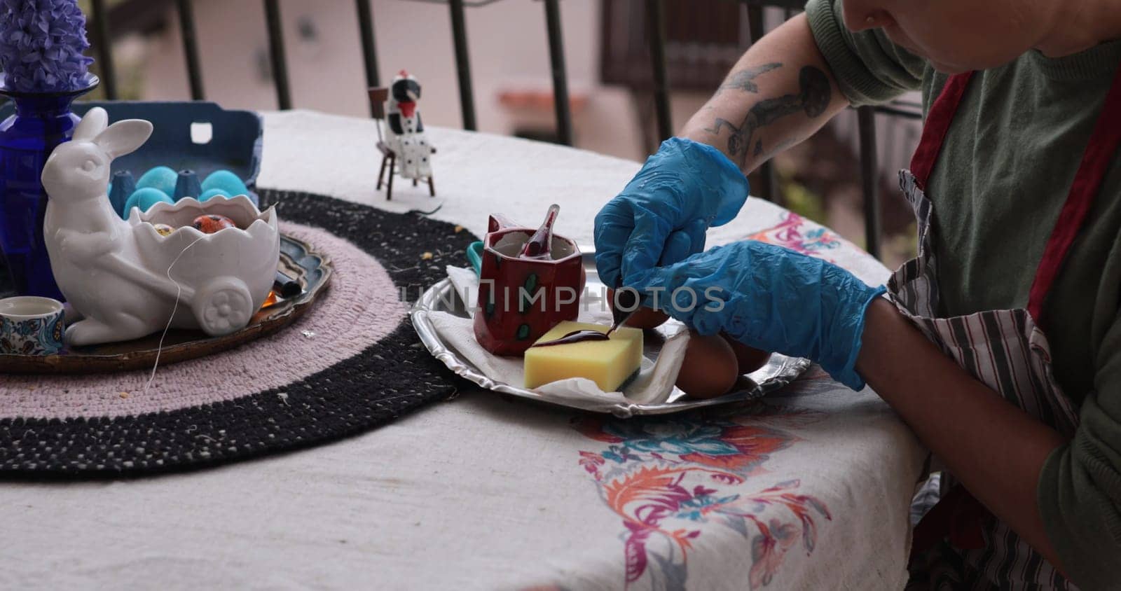 A person applies vibrant colors to red Easter eggs while preparing for the upcoming holiday.